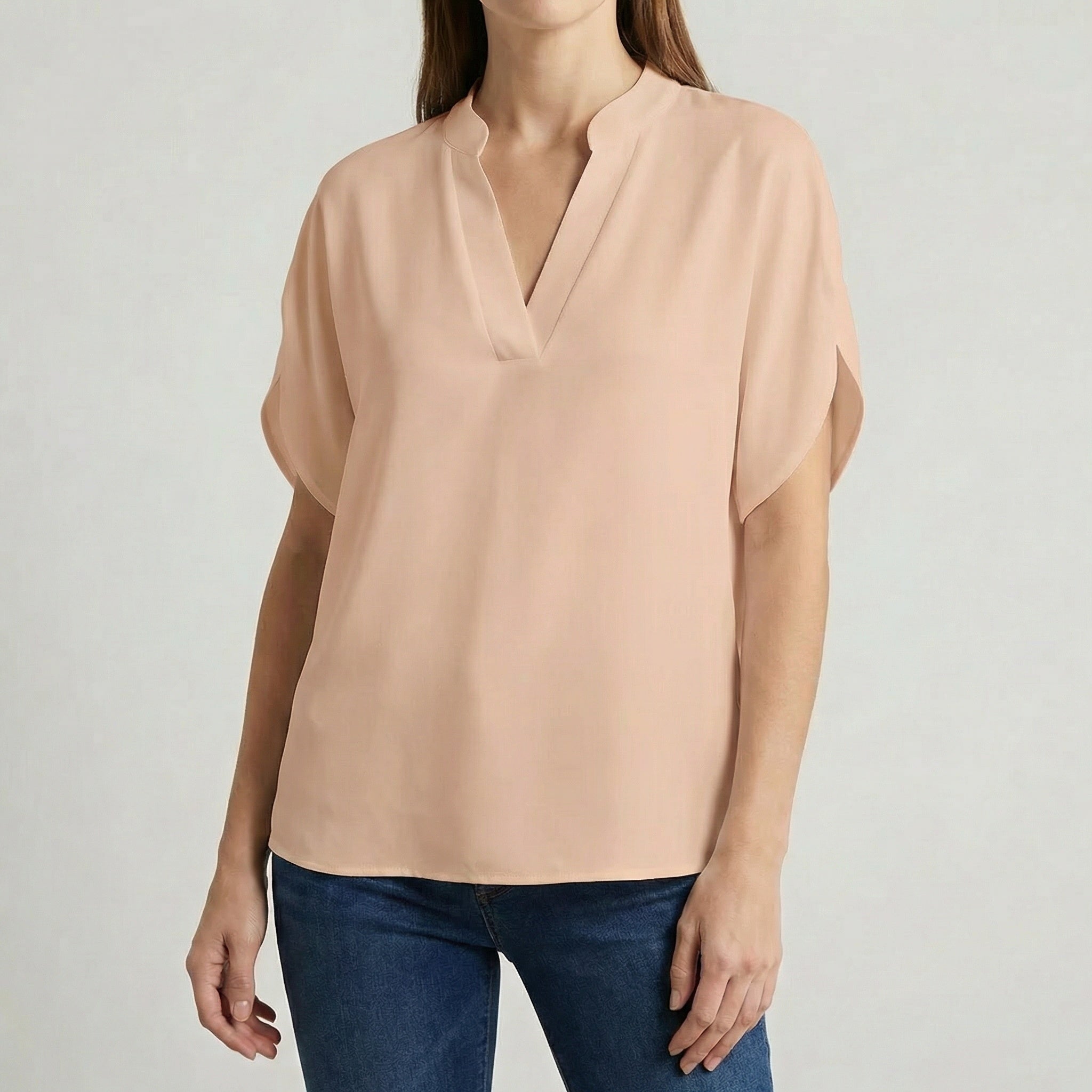 Blouse femme col en V avec manches fendues en beige nude, portée avec un jean bleu