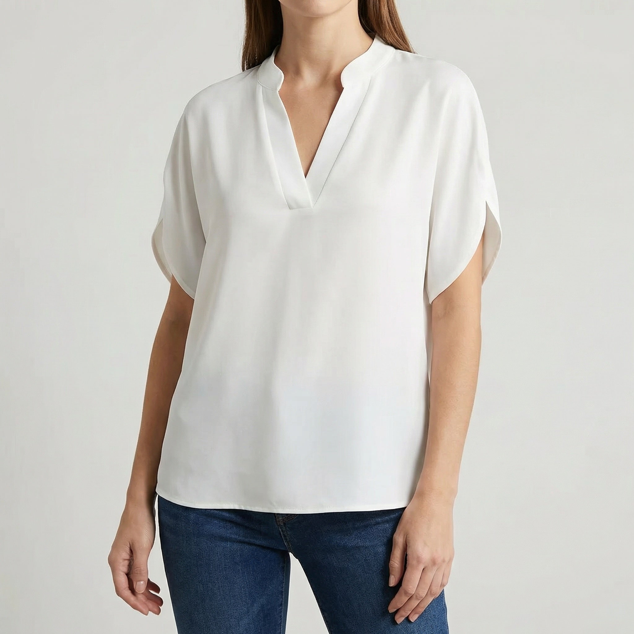 Blouse femme col en V avec manches fendues en blanc, portée avec un jean bleu