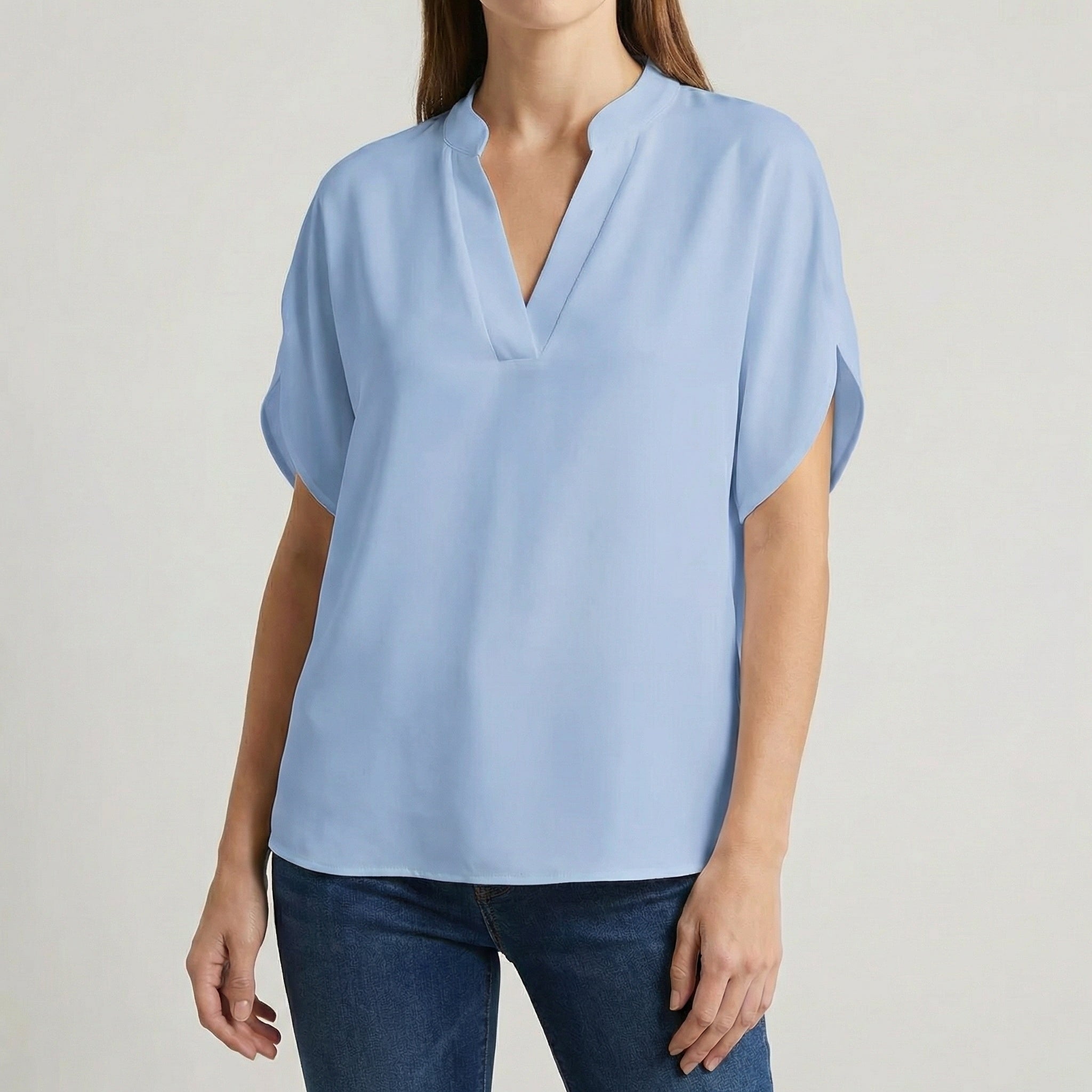 Blouse femme col en V avec manches fendues en bleu ciel, portée avec un jean bleu