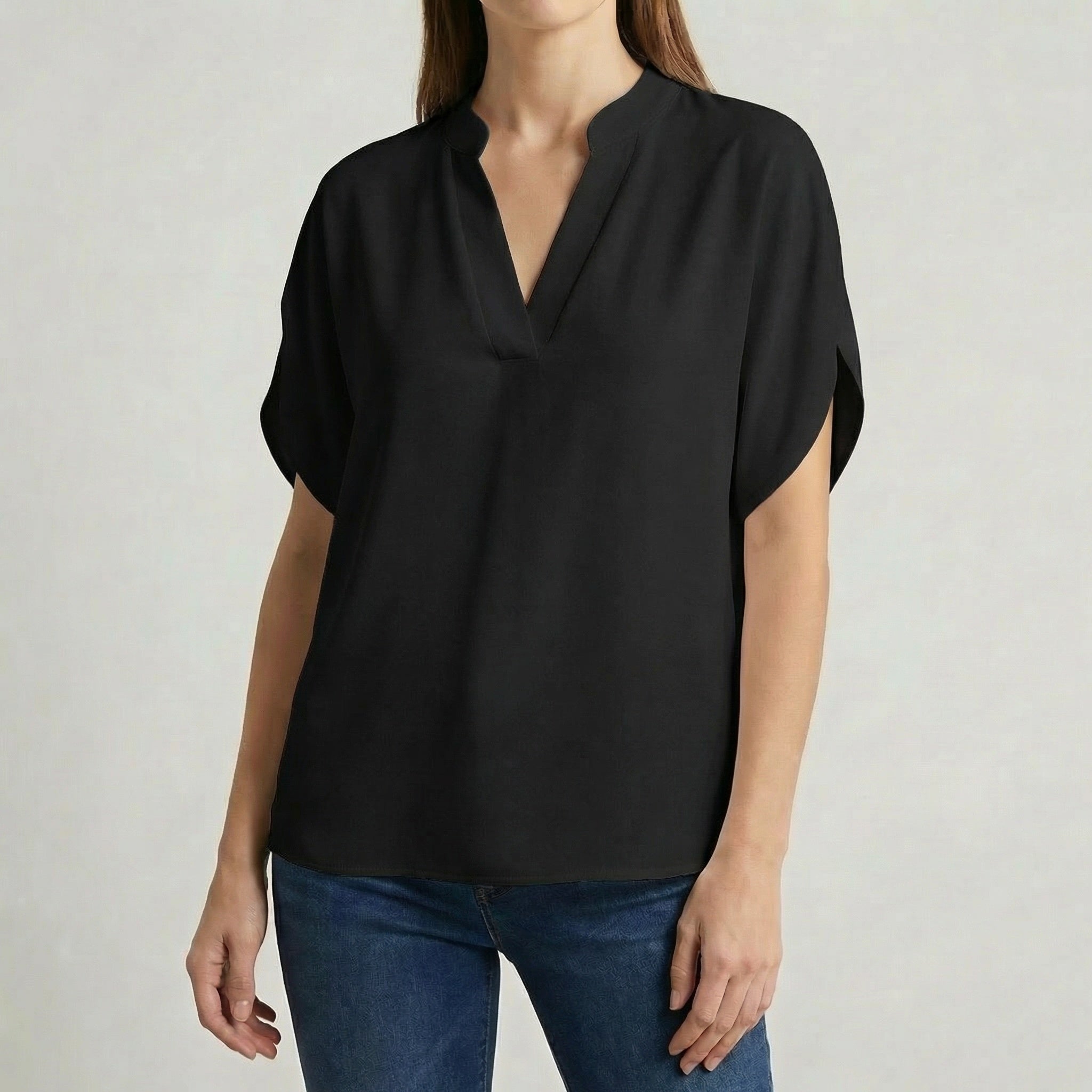 Blouse femme col en V avec manches fendues en noir, portée avec un jean bleu