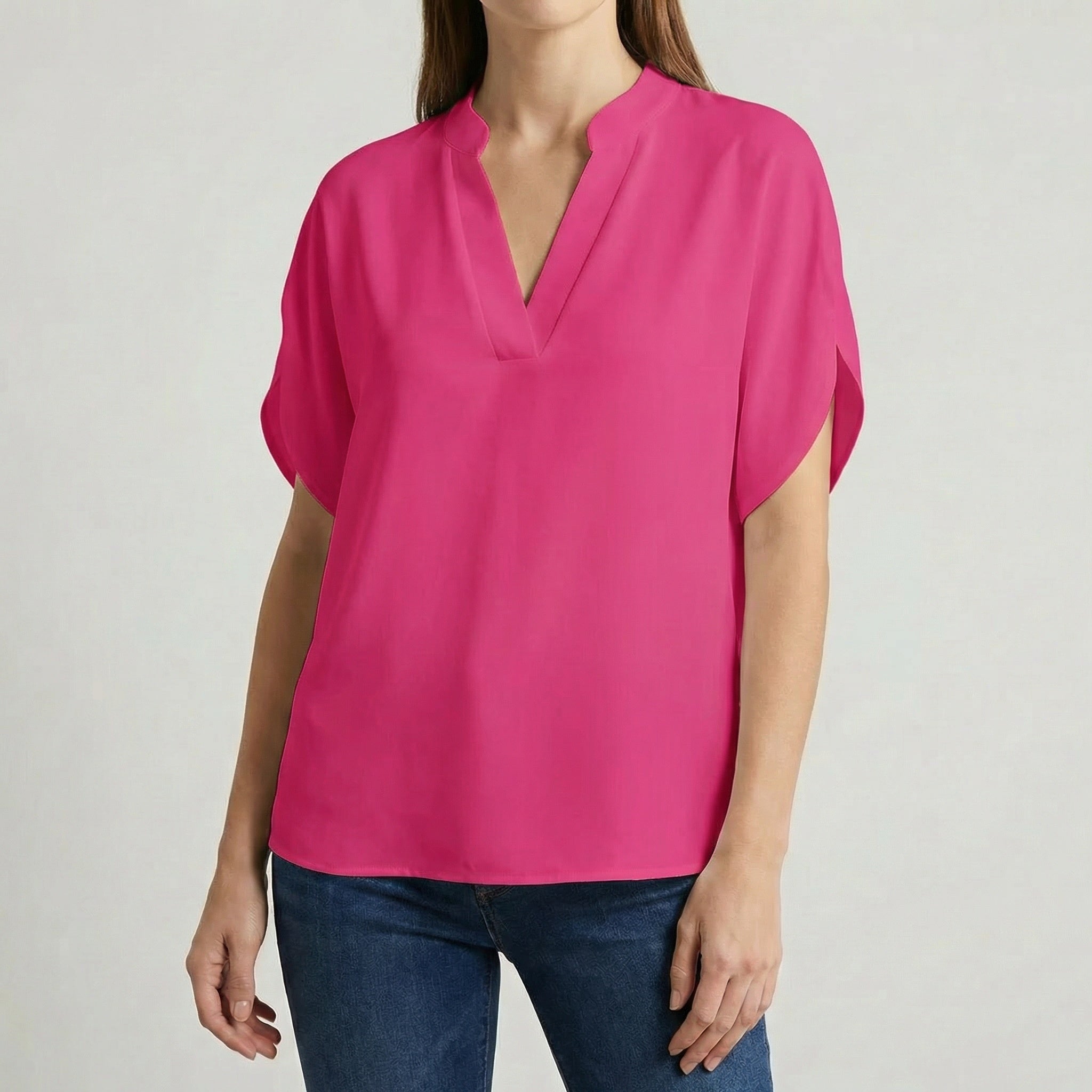 Blouse femme col en V avec manches fendues en rose fuchsia, portée avec un jean bleu