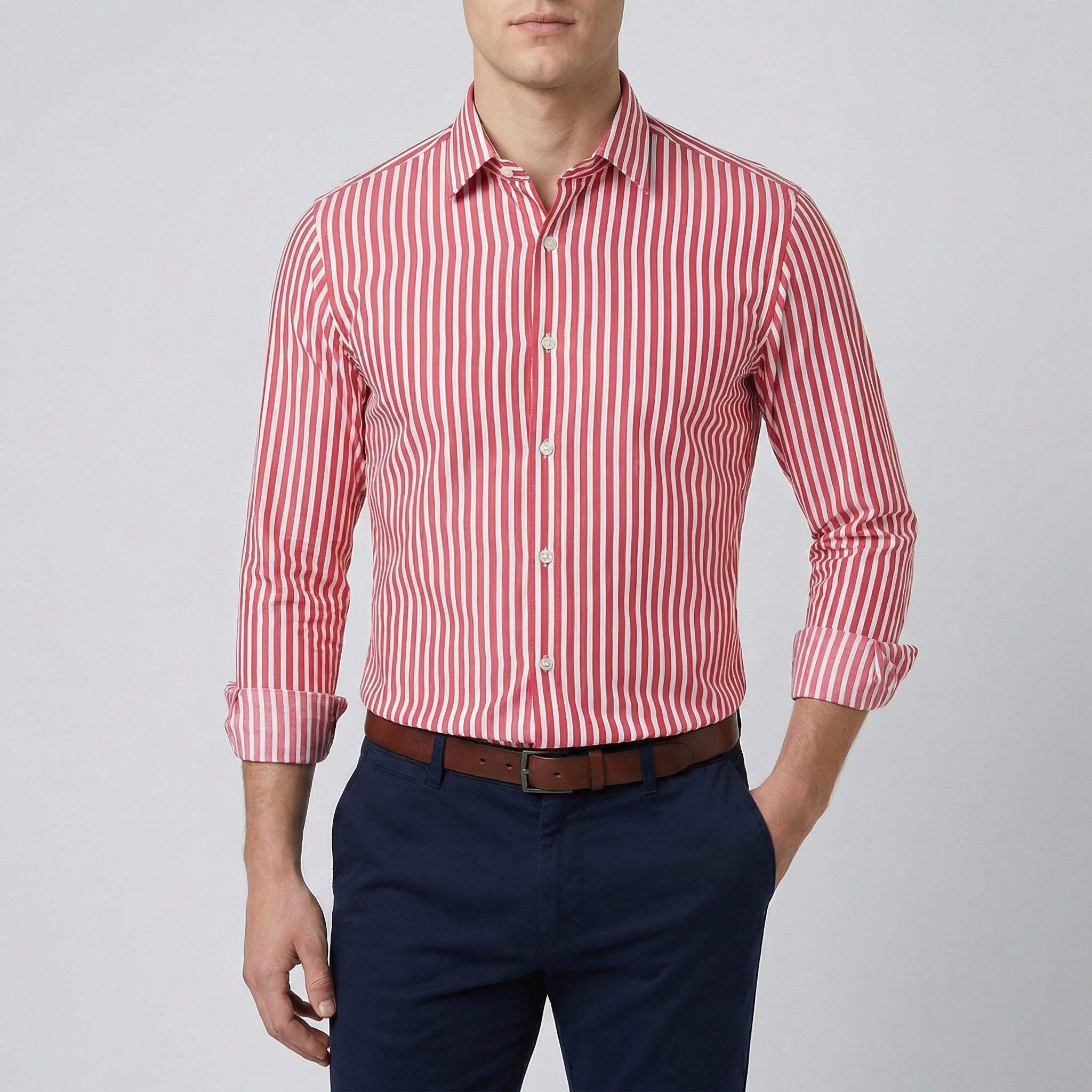 Chemise habillée à rayures rouge et blanches, coupe slim, manches longues retroussées, col boutonné, portée par un homme avec un pantalon marine et une ceinture marron.