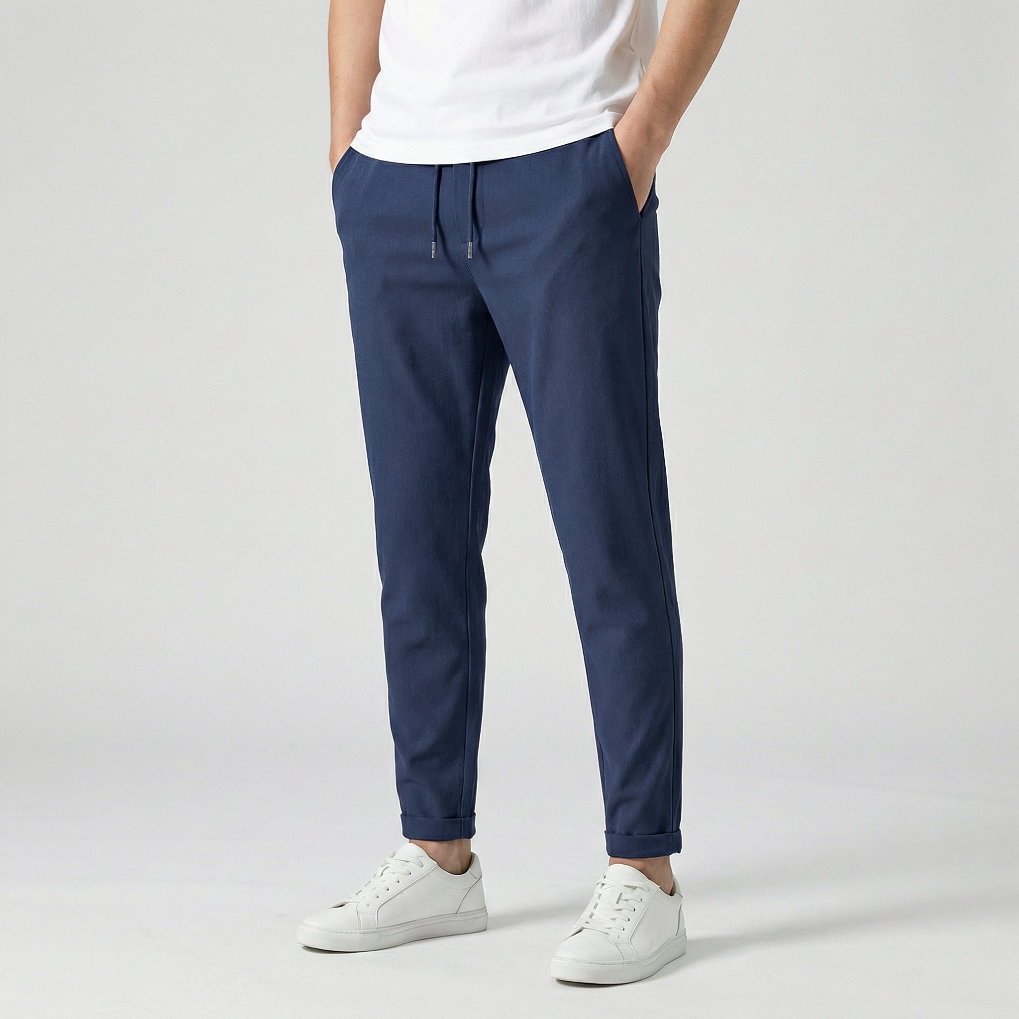 Pantalon jogger slim bleu marine avec cordon de serrage, porté par un homme en t-shirt blanc et baskets blanches