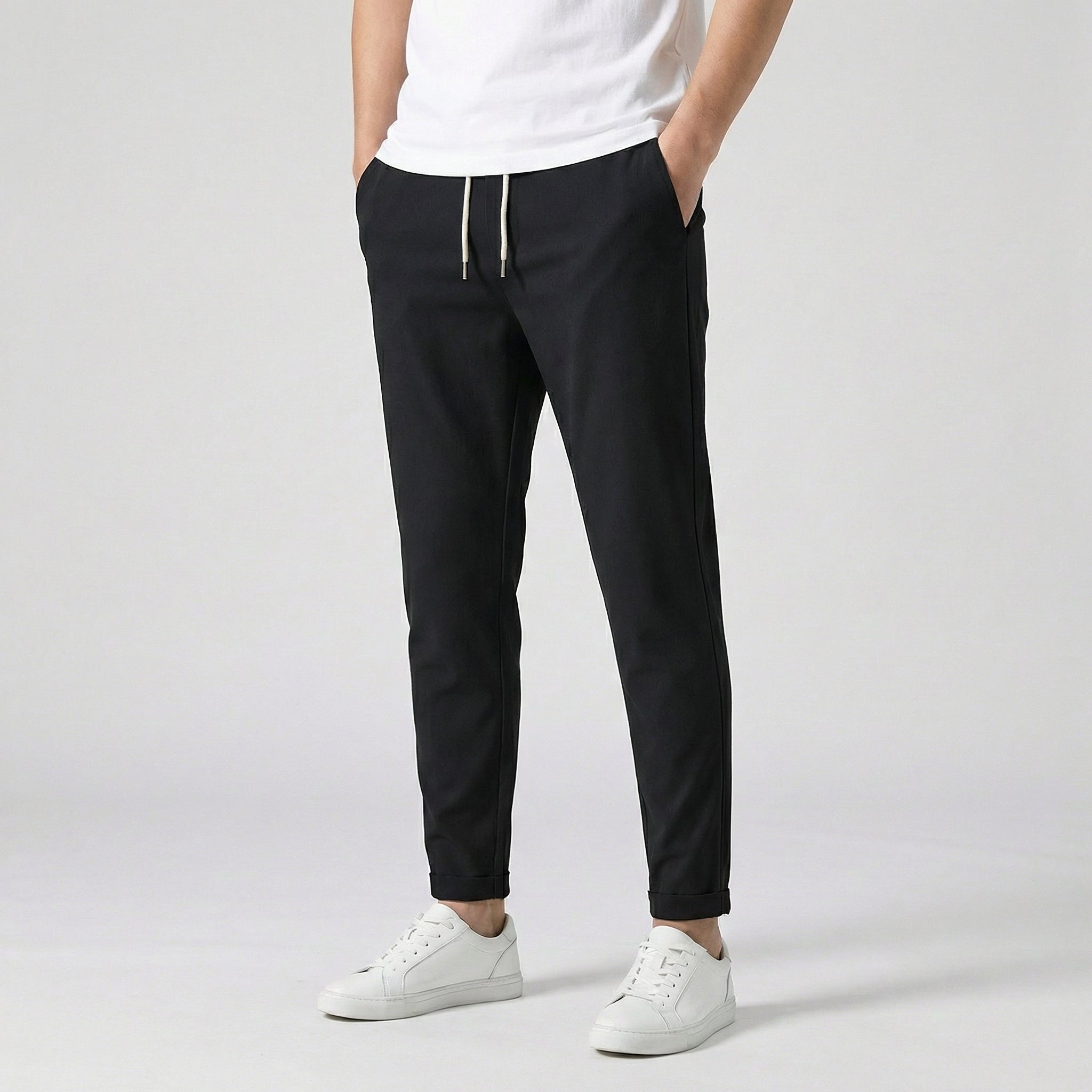 Pantalon jogger slim noir avec cordon de serrage noir, porté par un homme en t-shirt blanc et baskets blanches