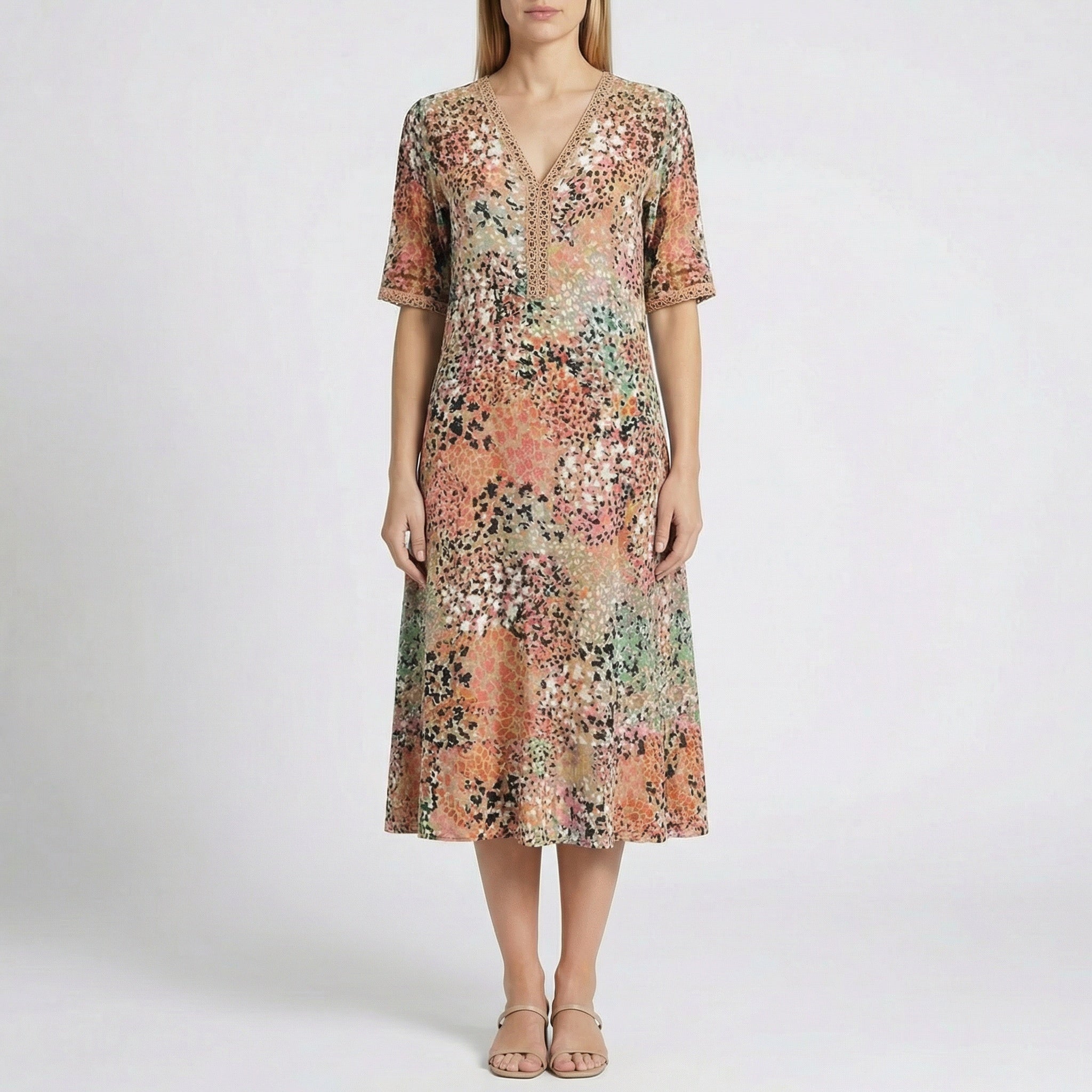 Robe midi Flore Beige à col en V, détails en dentelle et imprimé floral abstrait en beige, corail, rose, vert et noir, portée par un mannequin sur fond gris clair