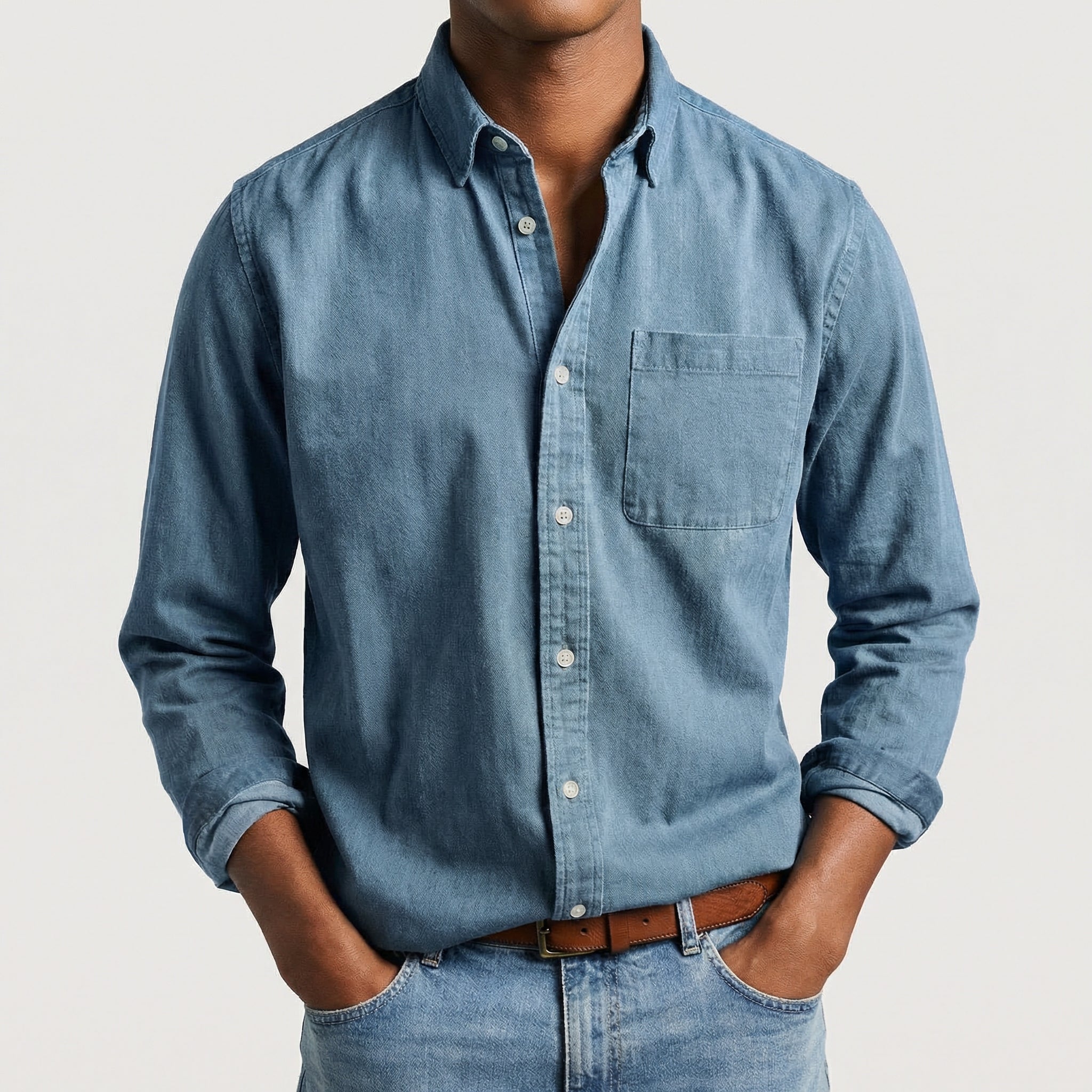 Chemise boutonnée manches longues en bleu ciel, portée par un mannequin masculin sans visage visible, pose décontractée, fond gris clair
