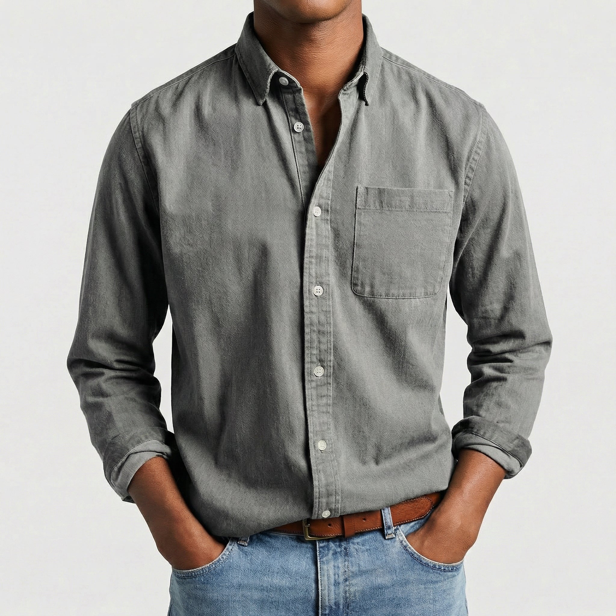 Chemise boutonnée manches longues en gris, portée par un mannequin masculin sans visage visible, pose décontractée, fond gris clair