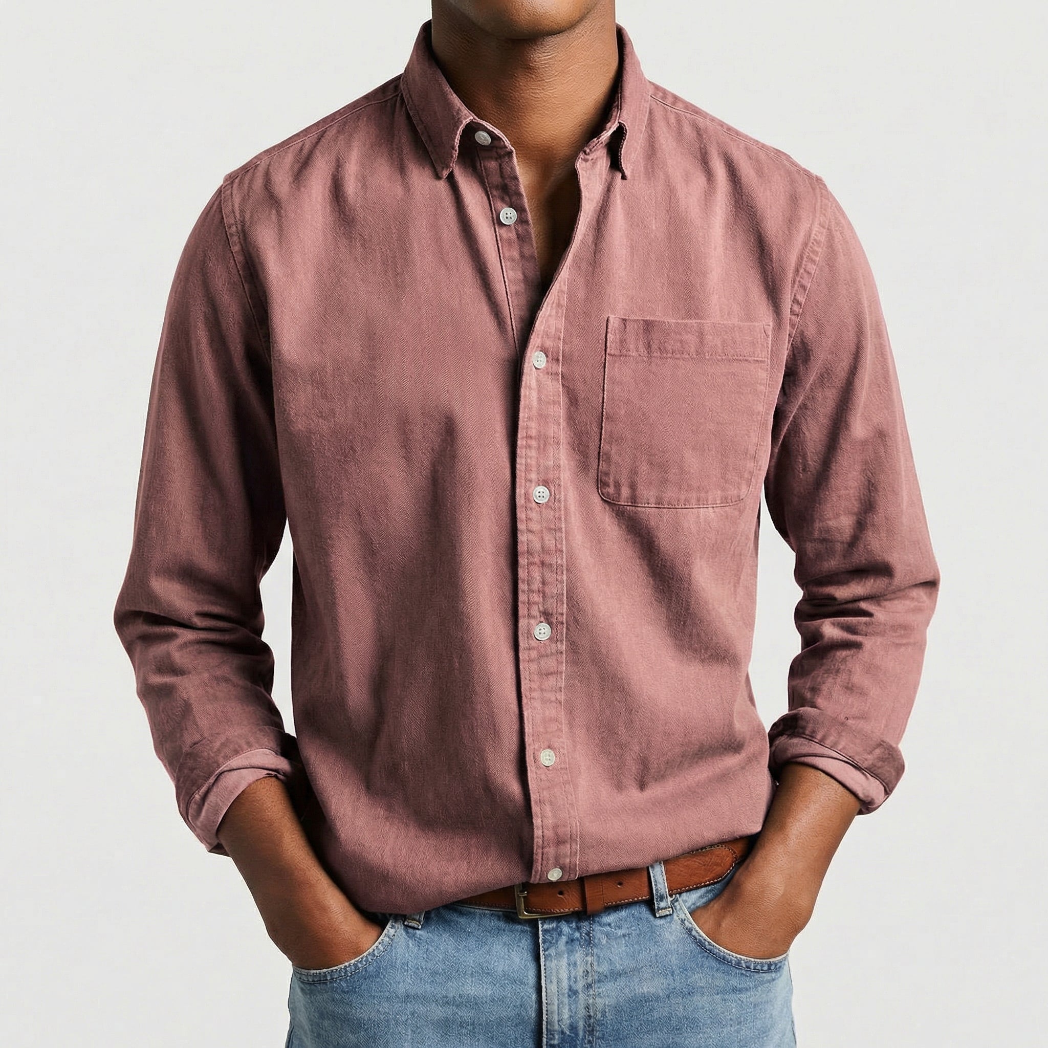 Chemise boutonnée manches longues en vieux rose, portée par un mannequin masculin sans visage visible, pose décontractée, fond gris clair