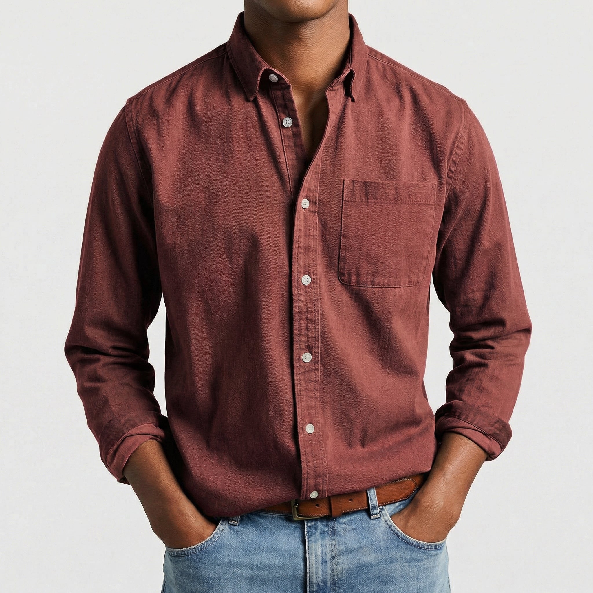 Chemise boutonnée manches longues en bordeaux, portée par un mannequin masculin sans visage visible, pose décontractée, fond gris clair
