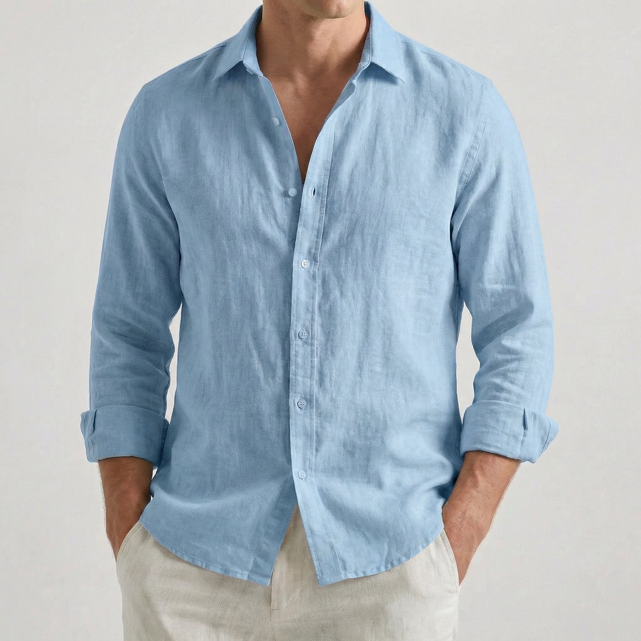 Chemise homme en lin à manches longues et col rabattu, coloris bleu ciel, portée par un mannequin masculin dans une pose décontractée sur fond gris clair