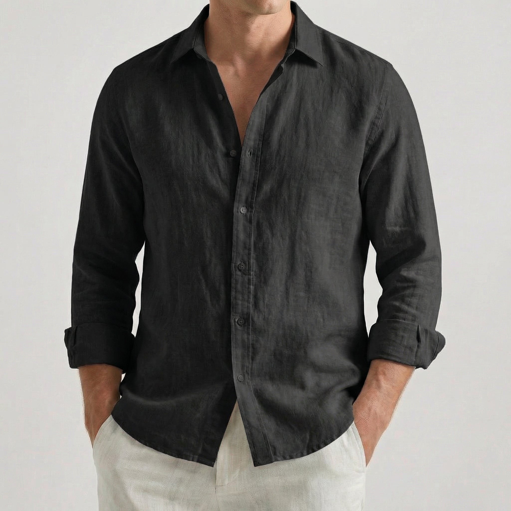 Chemise homme en lin à manches longues et col rabattu, coloris noir, portée par un mannequin masculin dans une pose décontractée sur fond gris clair
