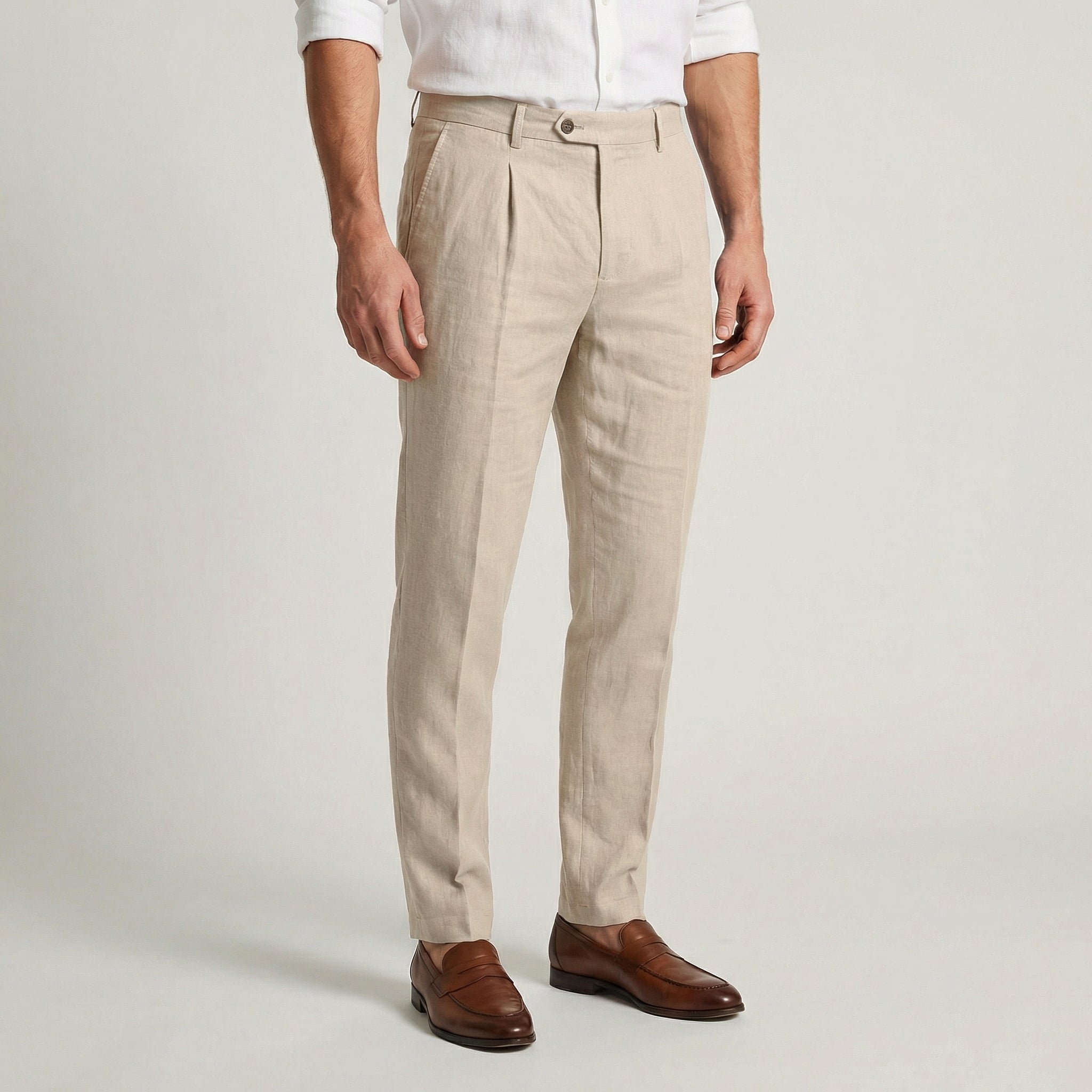 Pantalon en lin beige à pinces, coupe slim effilée, porté avec une chemise blanche et des mocassins en cuir marron