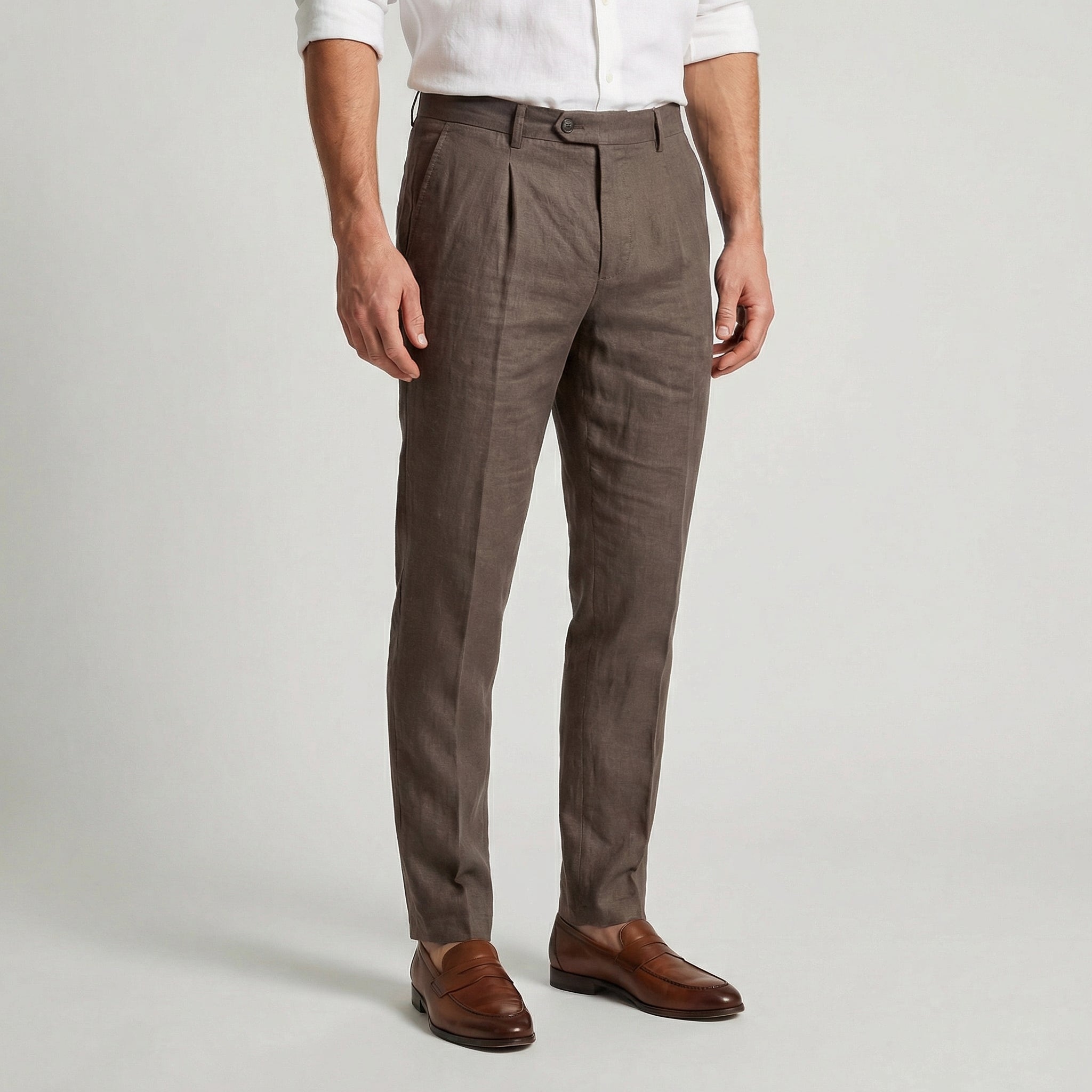 Pantalon en lin taupe à pinces, coupe slim effilée, porté avec une chemise blanche et des mocassins en cuir marron