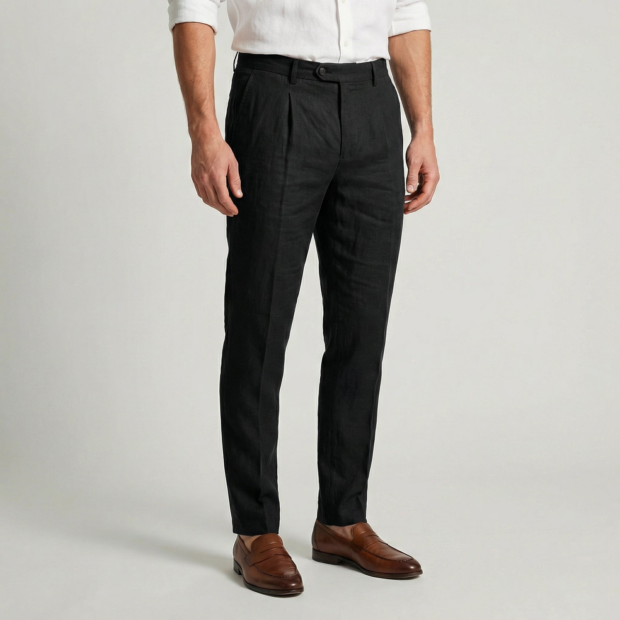 Pantalon en lin noir à pinces, coupe slim effilée, porté avec une chemise blanche et des mocassins en cuir marron