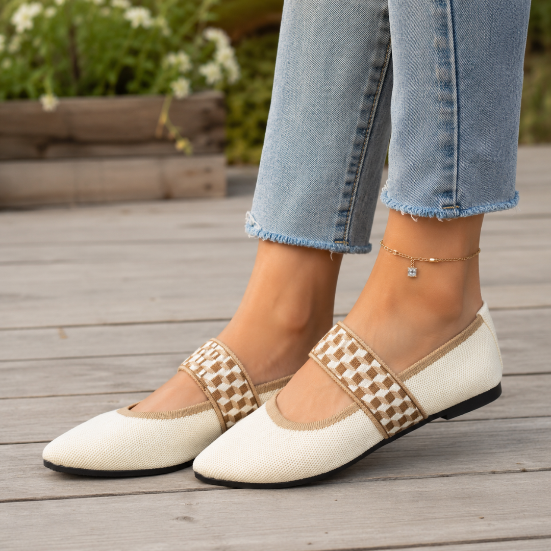 Ballerines blanches plates à bride damier, portées sur une terrasse en bois clair