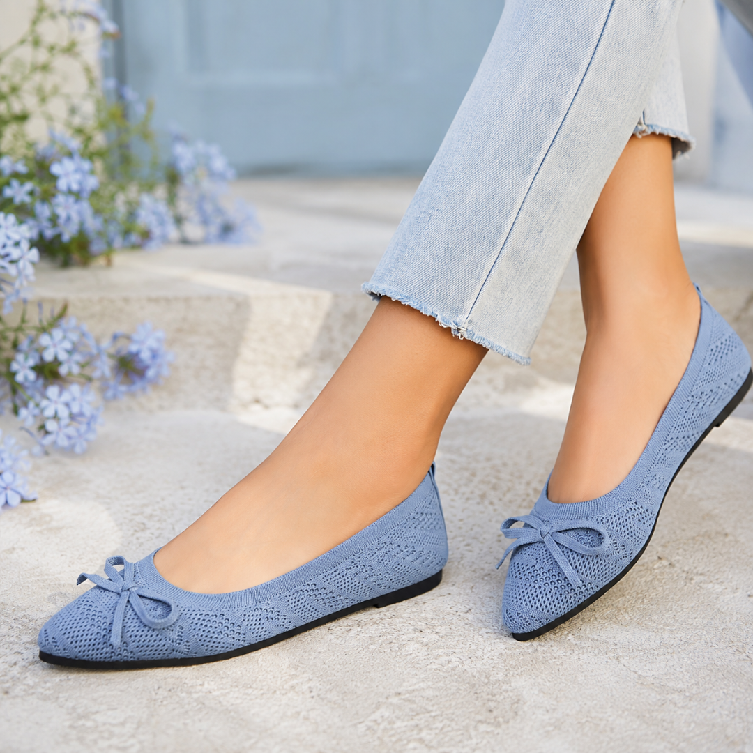 Ballerines bleu clair ajourées avec nœud fin, portées près de fleurs bleues