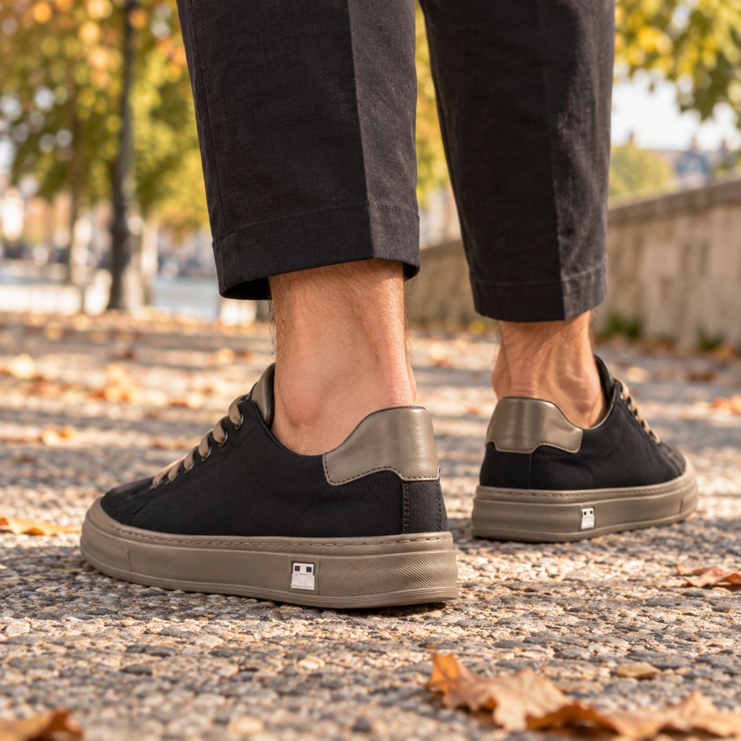 Vue arrière des baskets noires avec empiècement taupe au talon et semelle contrastante