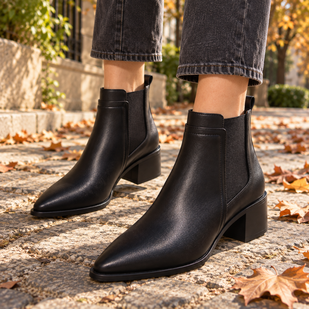 Gros plan des bottines noires à bout pointu et semelle fine sur pavés