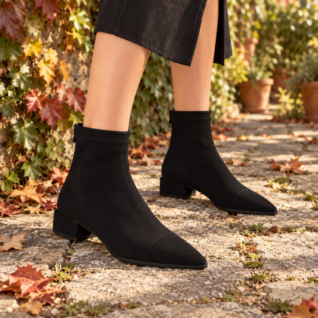 Bottines noires à bout pointu surpiqué sur pavés, feuilles d'automne au sol