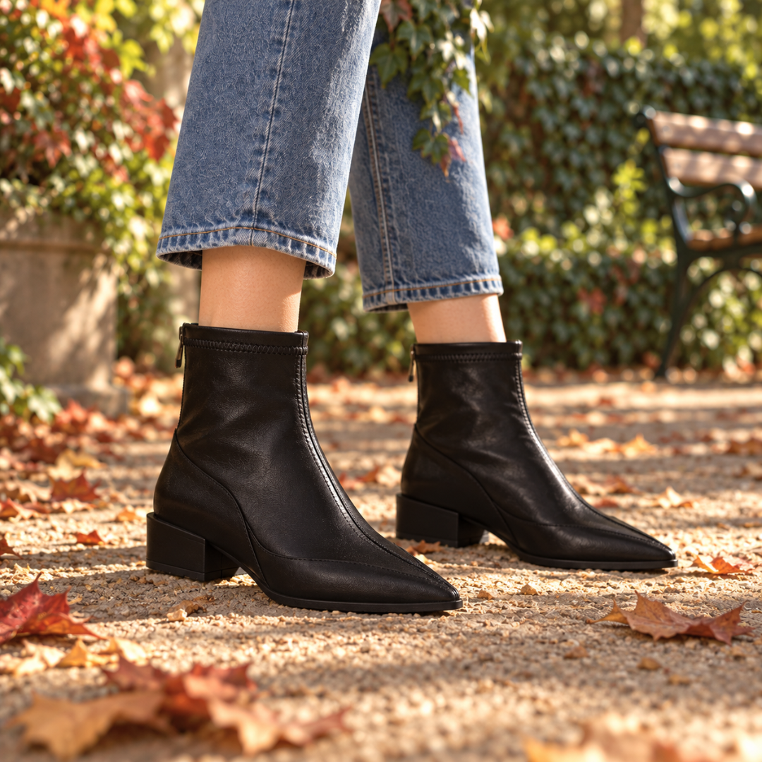 Bottines noires à bout pointu marchant sur un sol couvert de feuilles