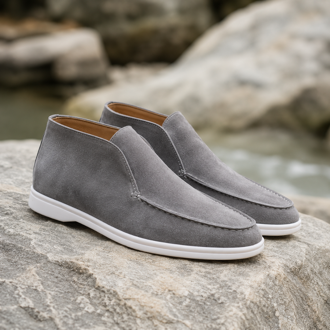 Bottines gris clair à enfiler, couture mocassin et semelle blanche sur un rocher