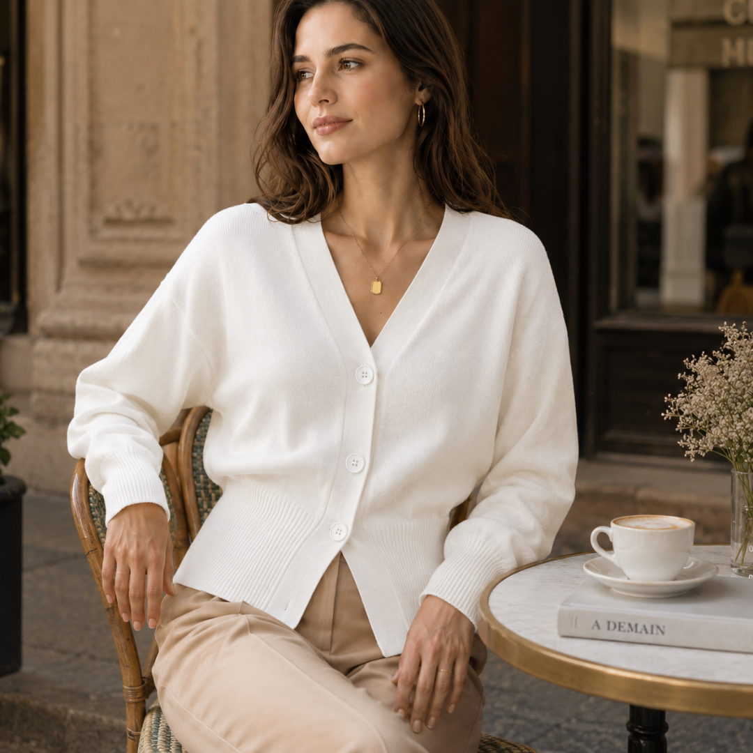 Femme assise en terrasse portant un cardigan blanc court à poignets côtelés