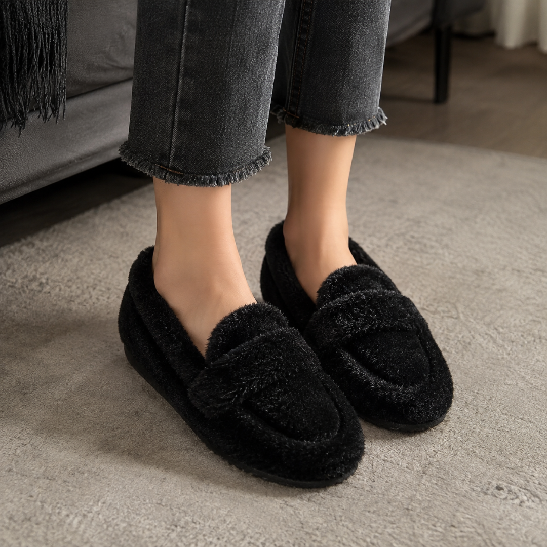 Chaussons femme noirs façon mocassin portés avec un pantalon gris, semelle plate