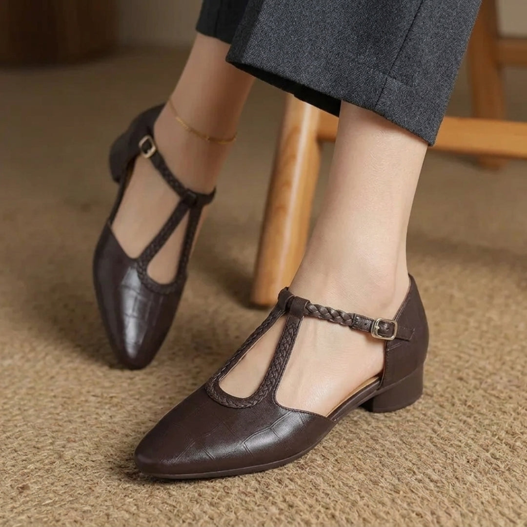 Paire de chaussures plates bride en T marron vues de trois quarts, portées assises