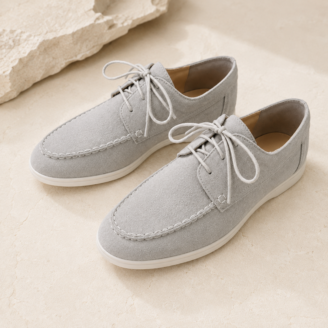 Paire de chaussures homme gris clair à lacets sur sol clair, bout arrondi surpiqué