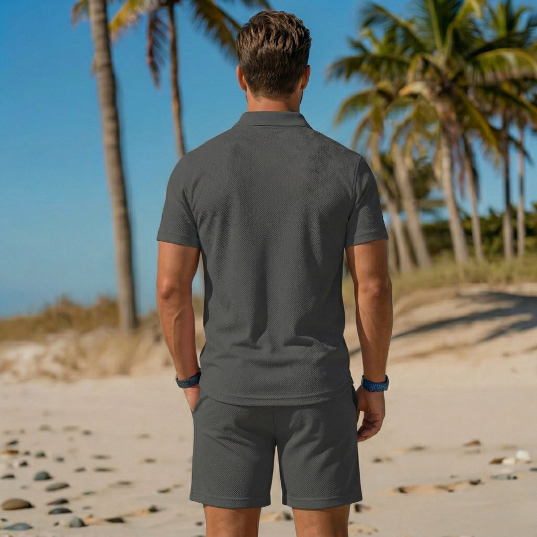 Ensemble homme polo et short gris foncé vue de dos face aux palmiers