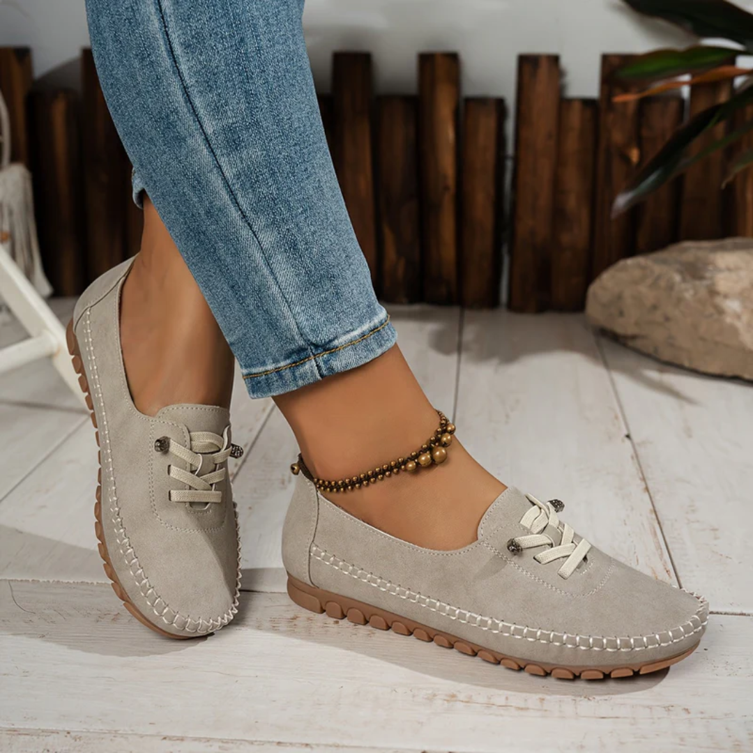 Paire de loafers beige posée sur sol clair, détail lacet décoratif