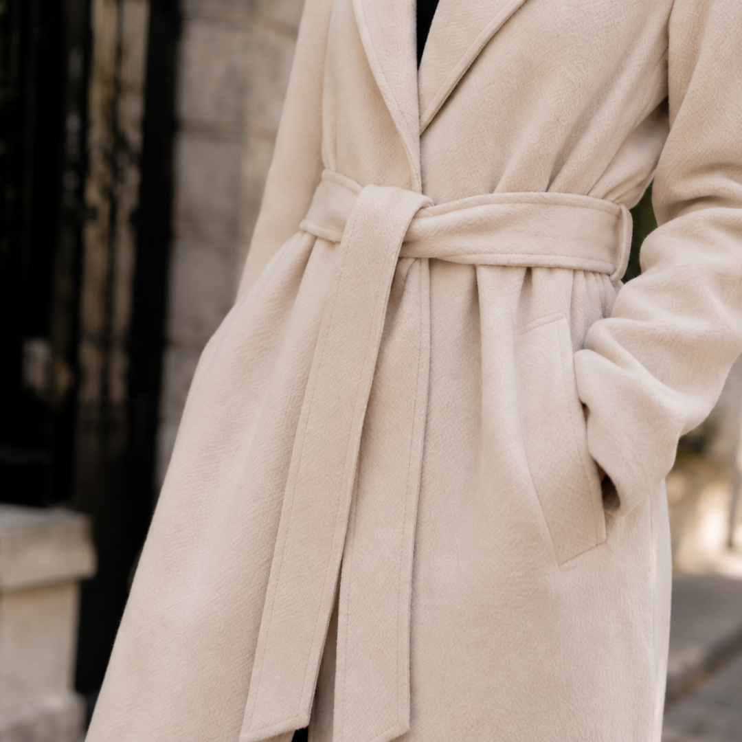 Gros plan sur la ceinture à nouer et la poche latérale du manteau beige