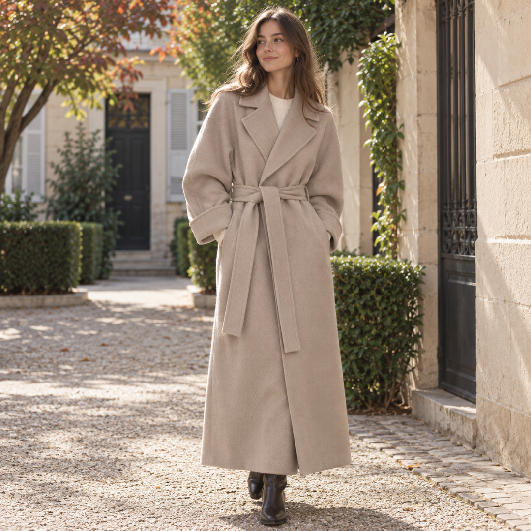 Manteau long abricot ouvert sur un pull clair, ceinture longue nouée devant