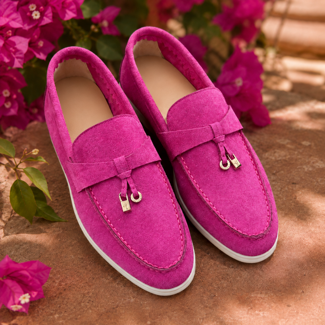 Mocassins femme rose vif devant des bougainvilliers, breloques dorées et semelle blanche