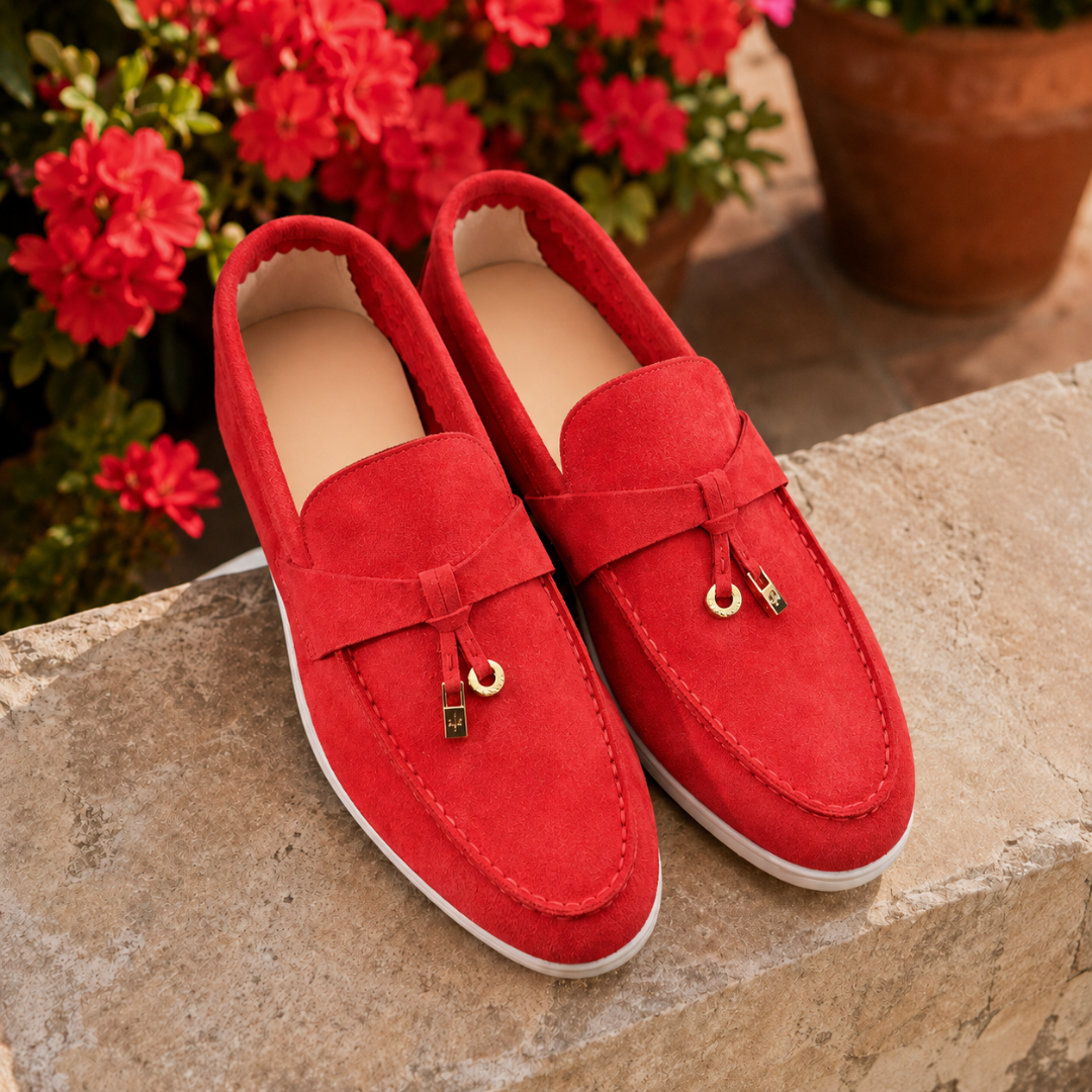 Mocassins femme rouges vus de dessus devant des fleurs, breloques dorées brillantes