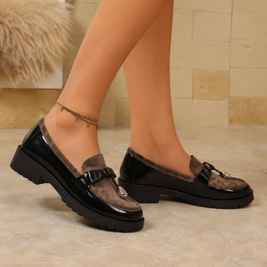 Mocassins femme noirs léopard portés de profil, talon bas et bride à breloque dorée