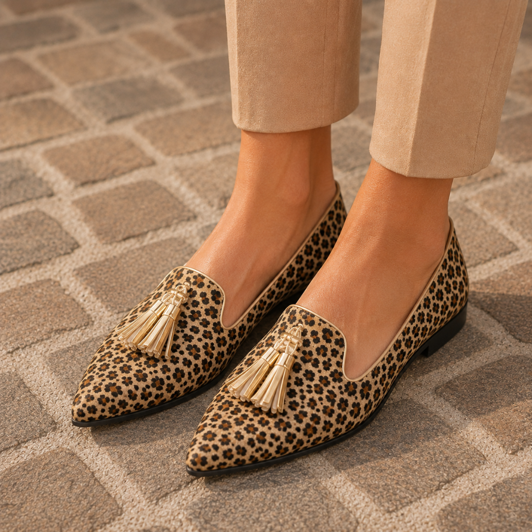 Mocassins plats léopard portés de trois quarts, pompons dorés sur le dessus