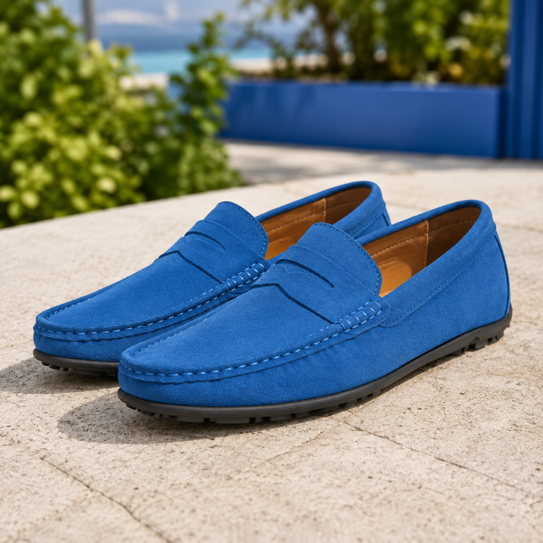 Mocassins homme bleu foncé éclatant, bande penny et semelle à picots, terrasse ensoleillée.