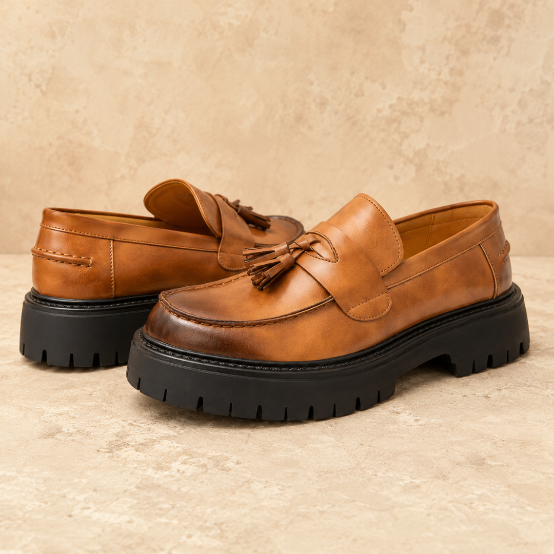 Mocassins cognac vus de côté, bout arrondi surpiqué et pompons décoratifs bien visibles