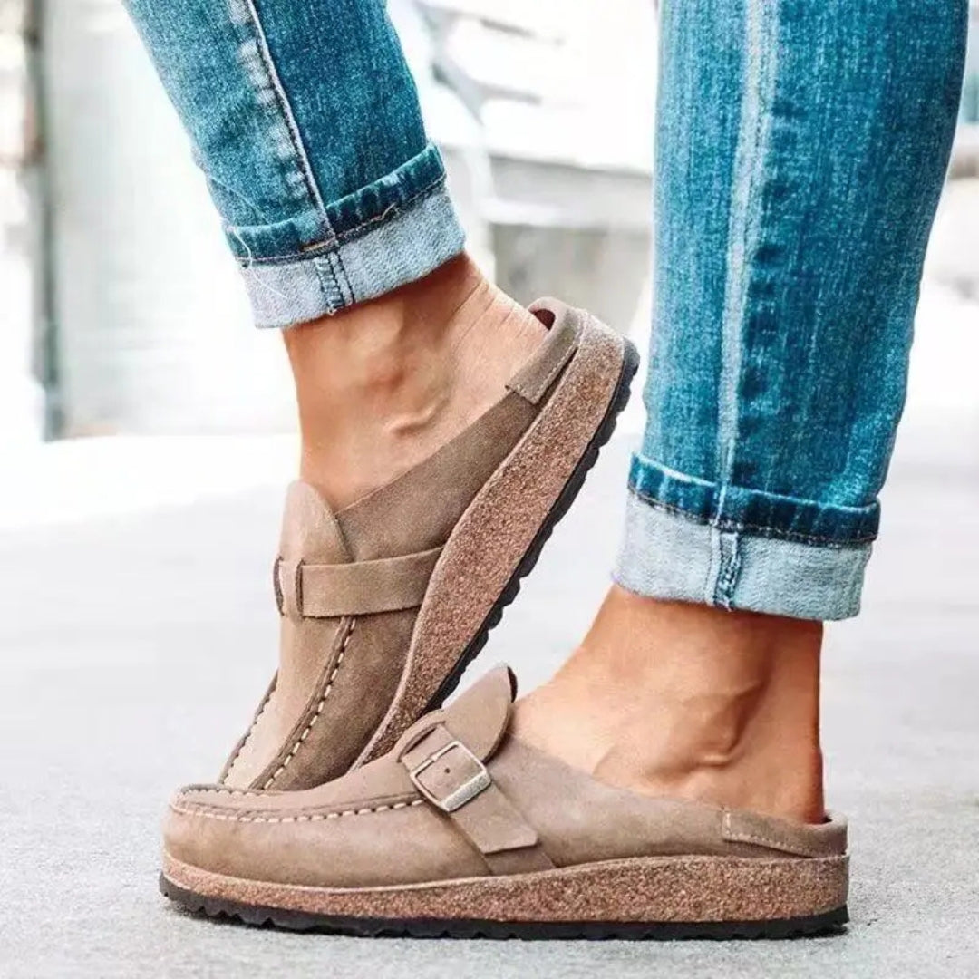 Paire de mules beige suédine posées sur surface claire, vue de trois quarts