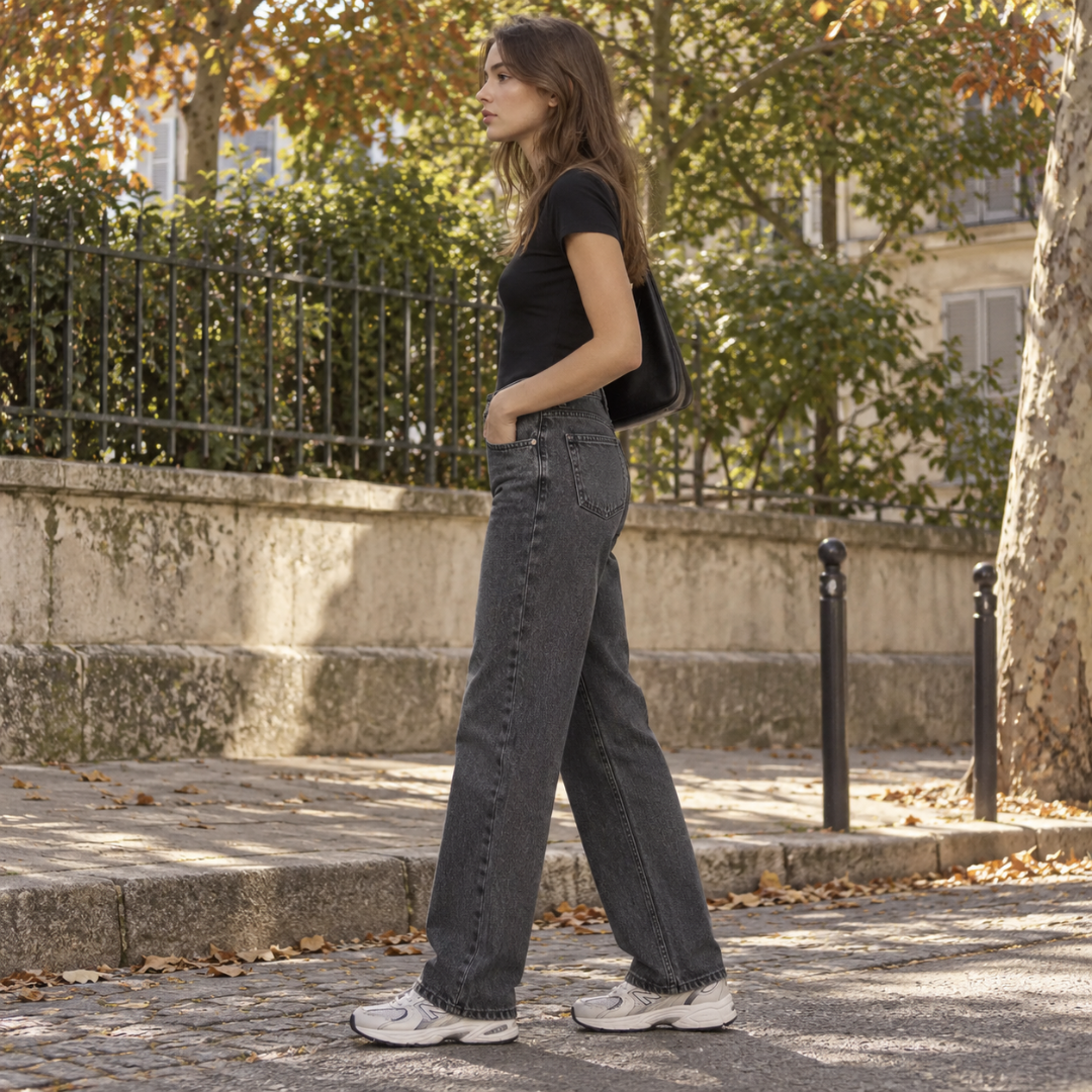Profil du pantalon femme noir délavé, jambe large tombant sur les baskets
