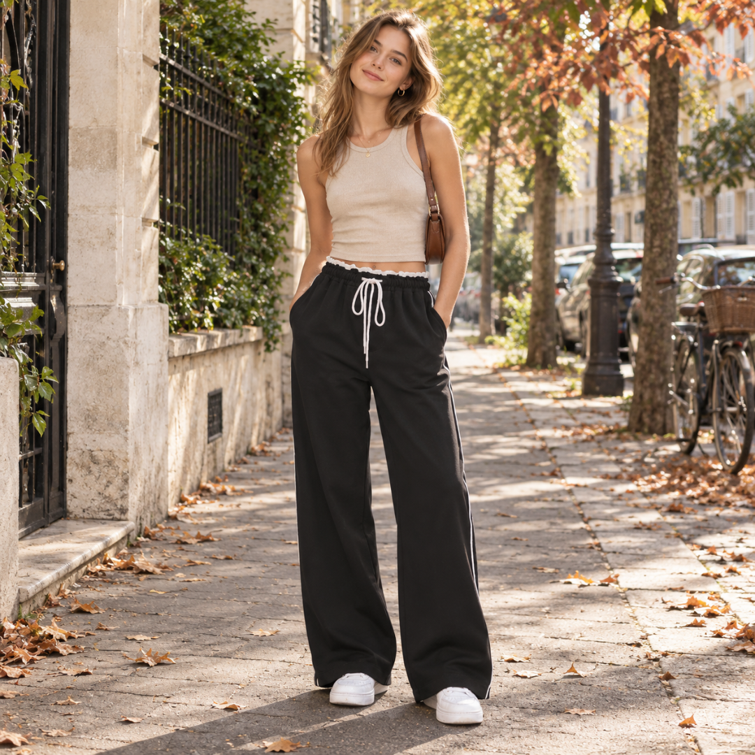 Pantalon femme large noir porté en rue, taille froncée à volant blanc