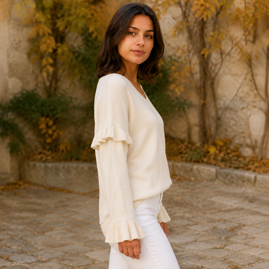 Profil du pull blanc, ligne souple et poignet évasé finement plissé