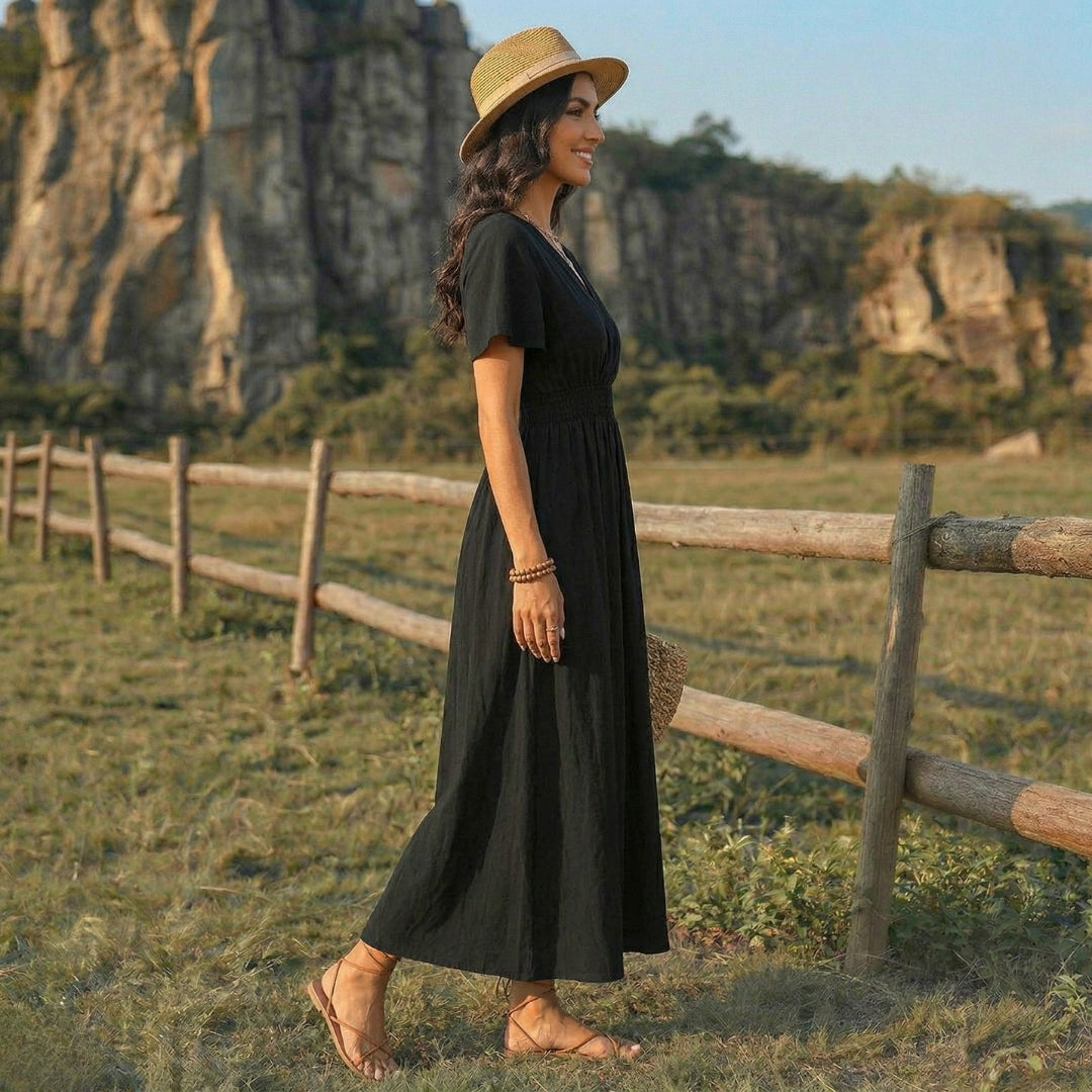 Femme en robe longue noire fluide marchant dans un paysage champêtre