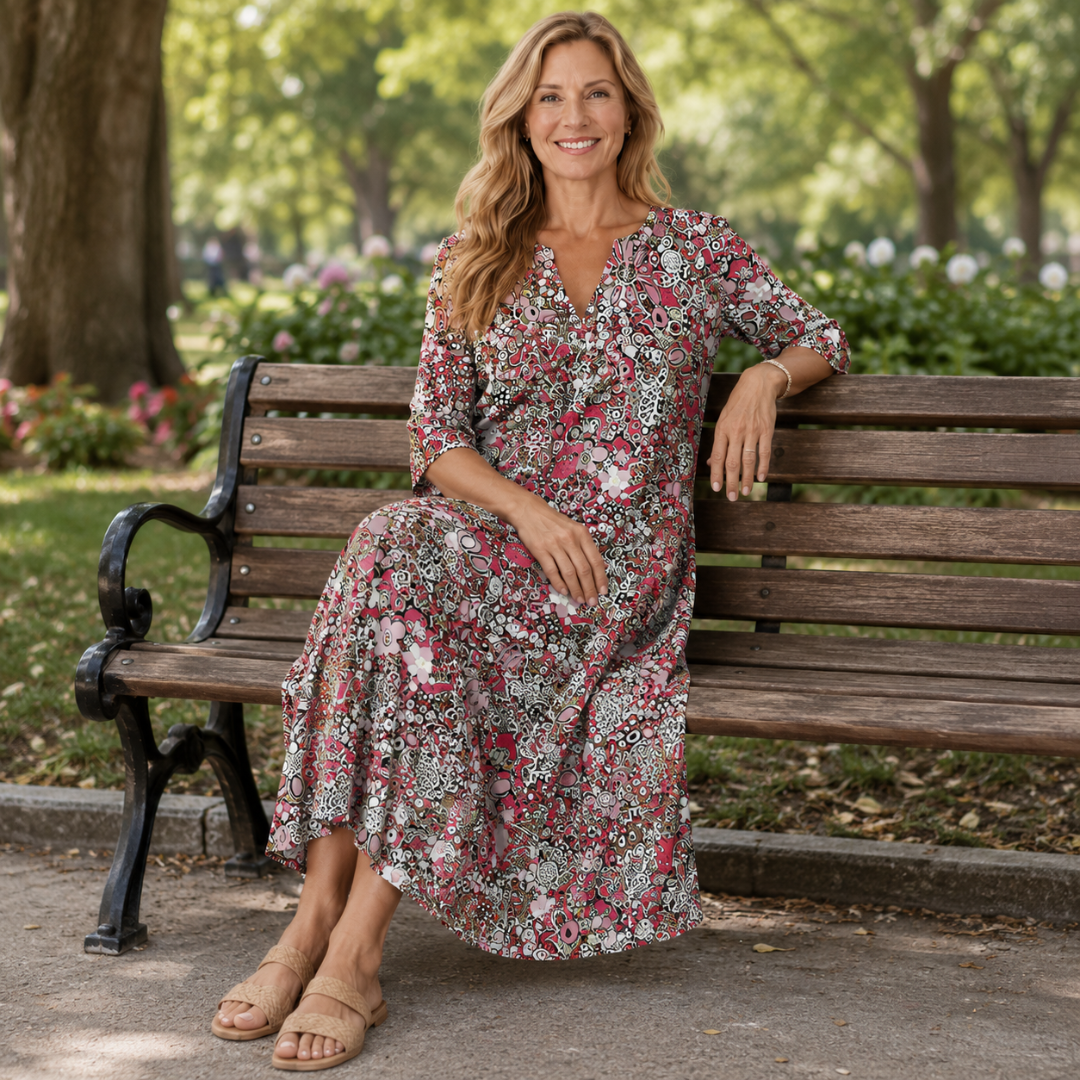Femme assise sur un banc portant une robe midi imprimé floral rouge et rose