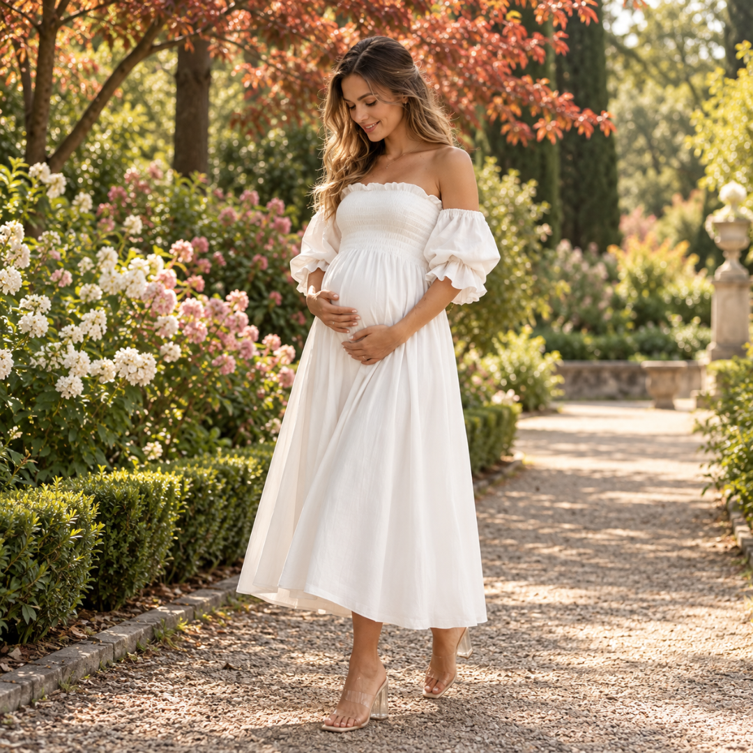 Robe de grossesse blanche midi, bustier smocké et manches ballon, allée fleurie