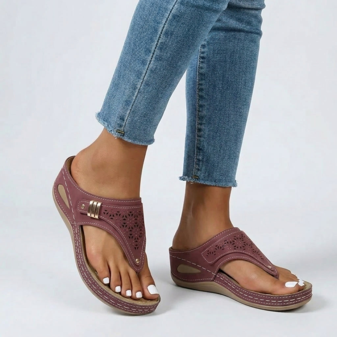 Sandales compensées rouge portées avec jean, motifs ajourés et lanière tong visibles