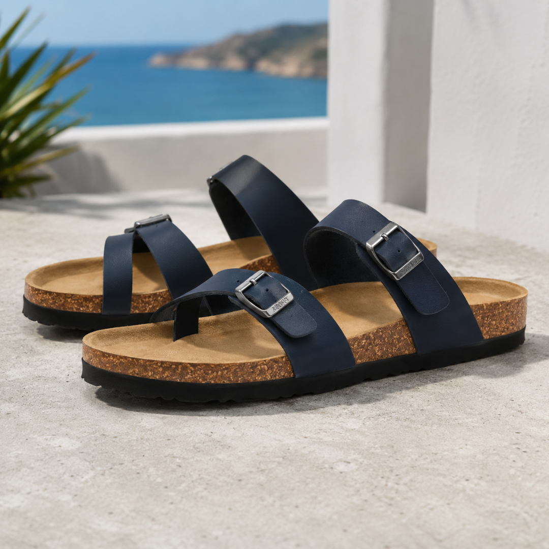 Sandales femme bleu marine à brides et boucles argentées, semelle liège devant l'océan