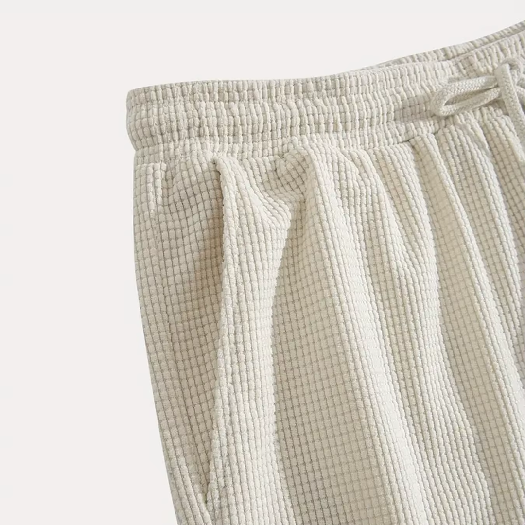 Détail du motif texturé beige et de la ceinture froncée du short homme