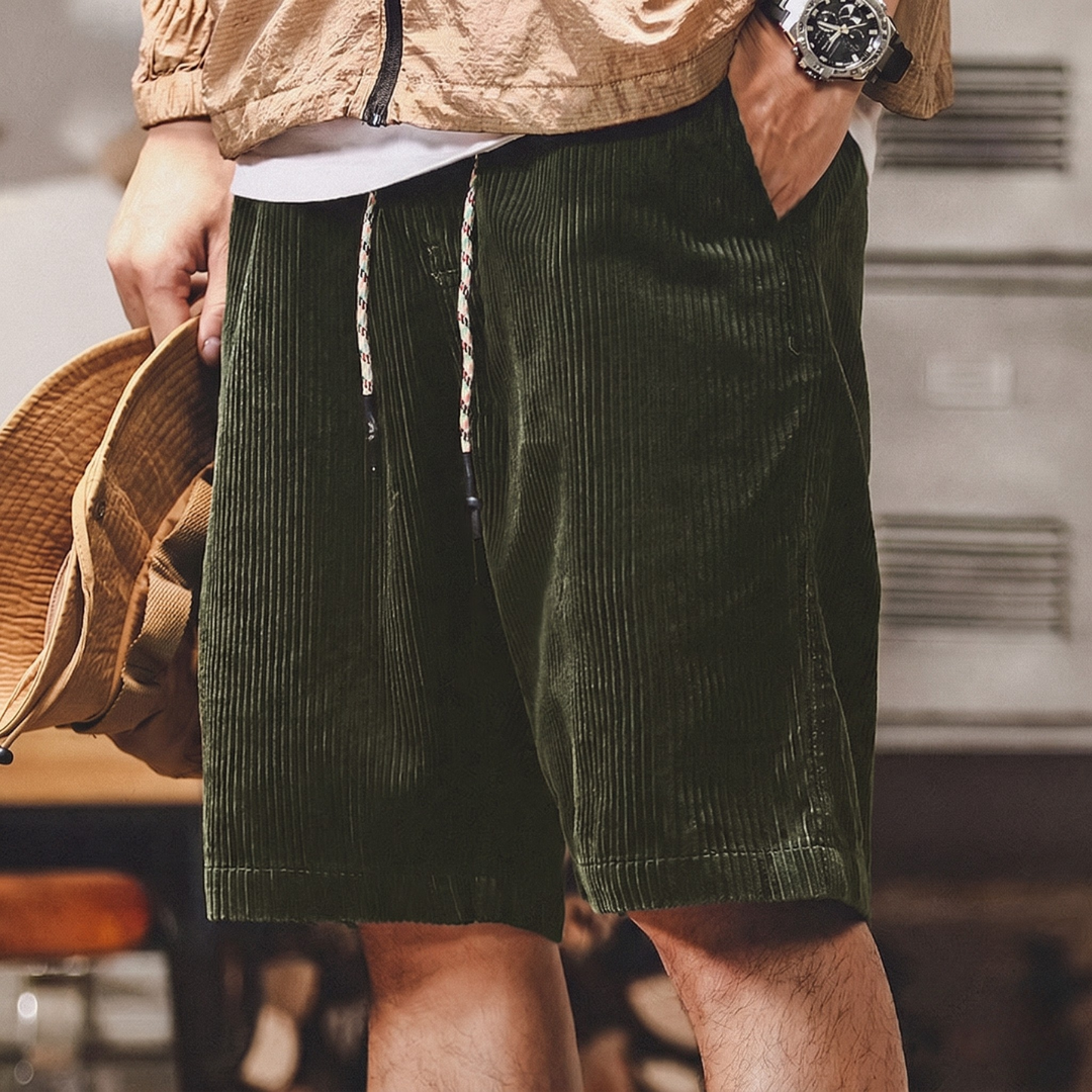 Short homme vert porté, vue de face sur fond foncé